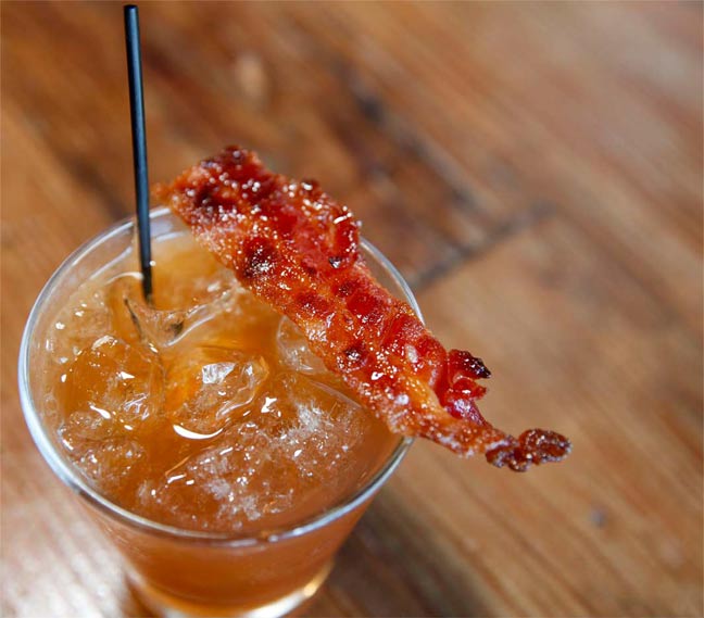 A drink with a piece of bacon on top.